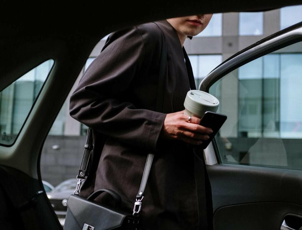 una donna con in mano un caffe in bicchiere monouso entra in swiss taxi castione