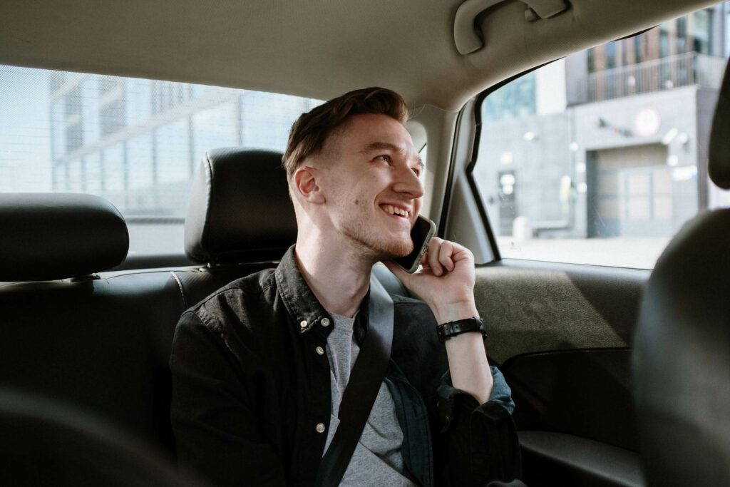 Un uomo in un taxi a giubiasco parla a telefono sorridendo